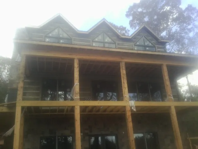 Dormers and porch framing on a large log home under construction — Roof Coating work by our crew in Caledonia